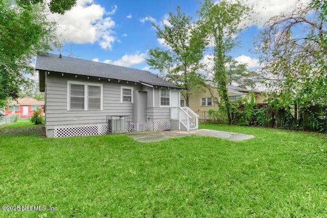 rear view of property with a yard and central air condition unit