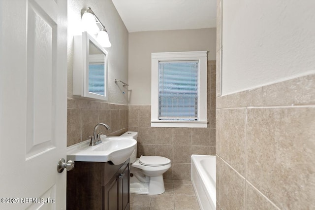 bathroom featuring tile walls, vanity, tile patterned floors, a tub, and toilet