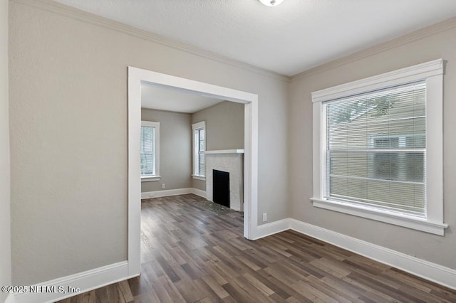 unfurnished living room featuring crown molding, a fireplace, and dark hardwood / wood-style floors