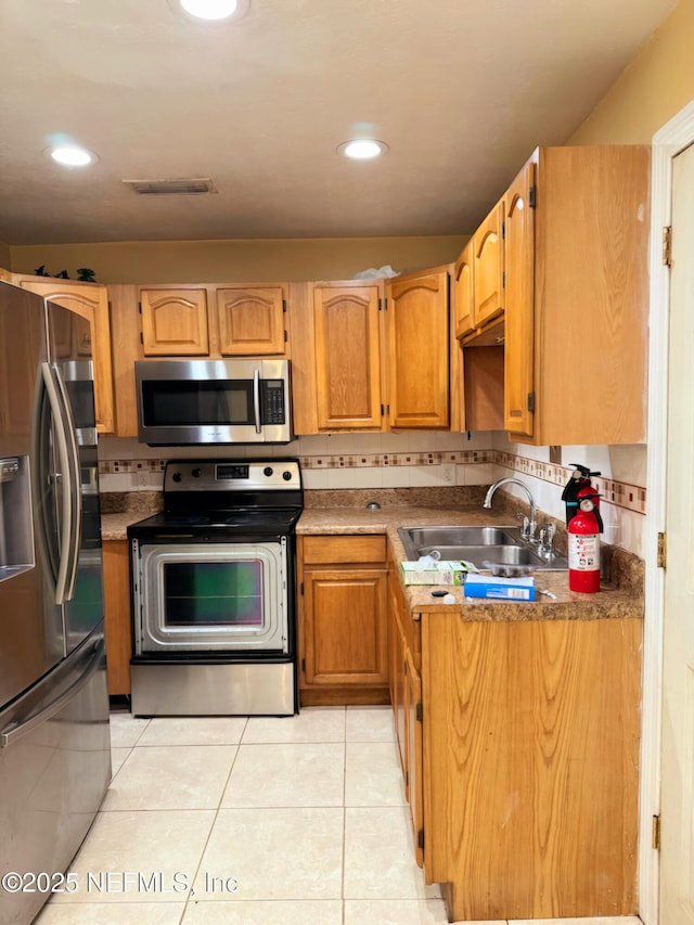 kitchen with stainless steel appliances, tasteful backsplash, sink, and light tile patterned floors