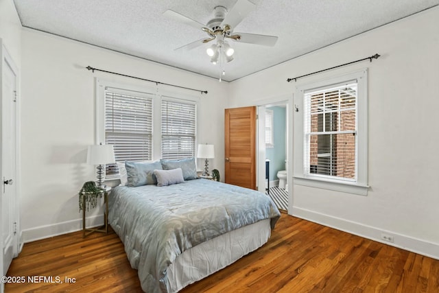 bedroom featuring ceiling fan, ensuite bathroom, dark hardwood / wood-style floors, and a textured ceiling