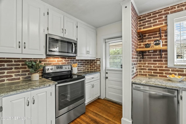 kitchen with white cabinetry, plenty of natural light, brick wall, and appliances with stainless steel finishes