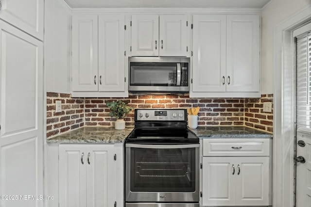 kitchen featuring dark stone countertops, stainless steel appliances, and white cabinets