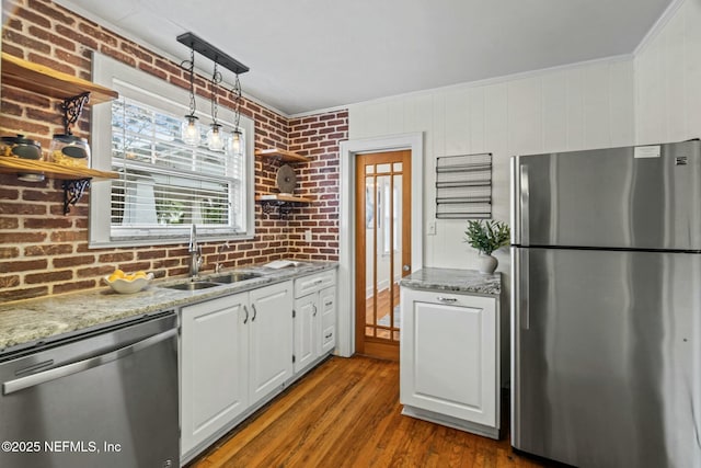 kitchen with hanging light fixtures, appliances with stainless steel finishes, sink, and white cabinets