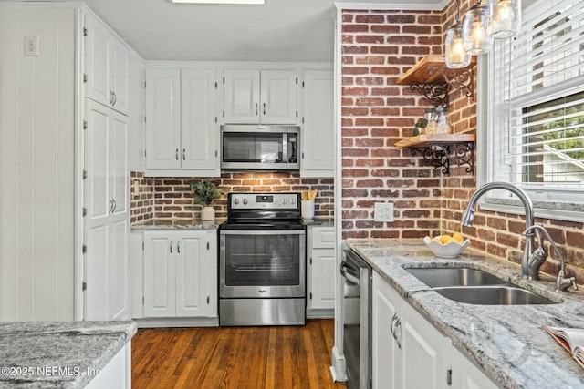 kitchen with white cabinetry, stainless steel appliances, light stone countertops, and sink