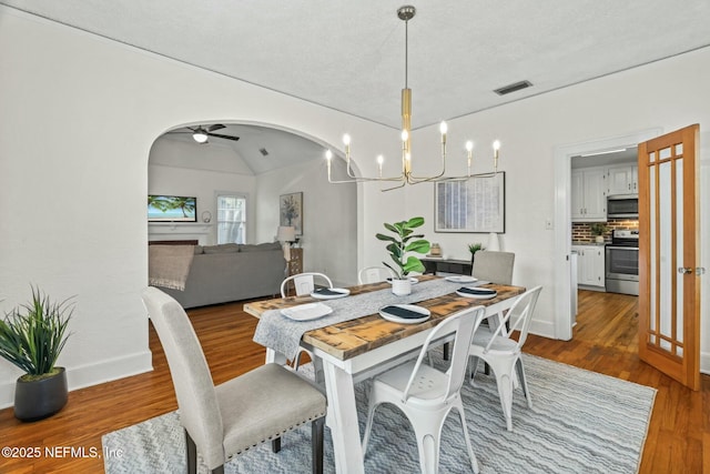 dining space with hardwood / wood-style flooring, vaulted ceiling, and ceiling fan with notable chandelier