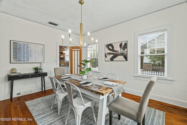 dining area featuring dark wood-type flooring, a chandelier, a textured ceiling, and a wealth of natural light