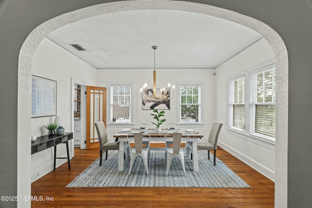 dining room featuring wood-type flooring, a textured ceiling, and an inviting chandelier