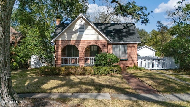 english style home featuring a porch and a front lawn