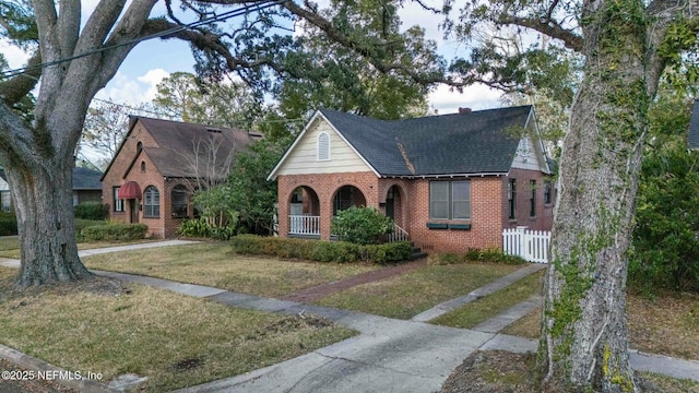 tudor house featuring a front lawn and covered porch