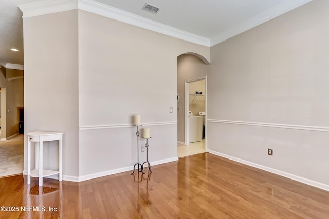 unfurnished room featuring visible vents, baseboards, ornamental molding, wood finished floors, and arched walkways