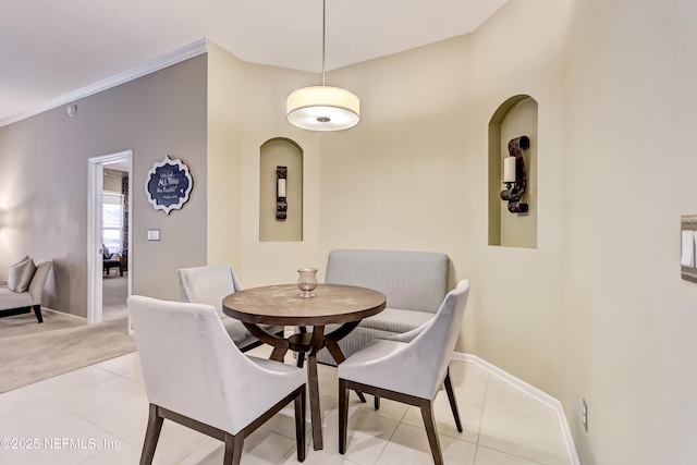 dining room featuring light tile patterned floors, baseboards, light colored carpet, and ornamental molding