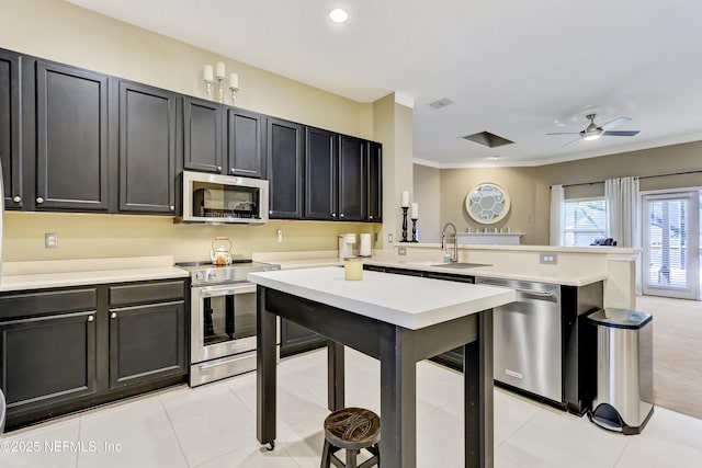 kitchen with ornamental molding, stainless steel appliances, a peninsula, light countertops, and ceiling fan