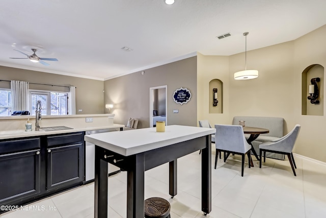 kitchen featuring a ceiling fan, visible vents, a sink, light countertops, and crown molding