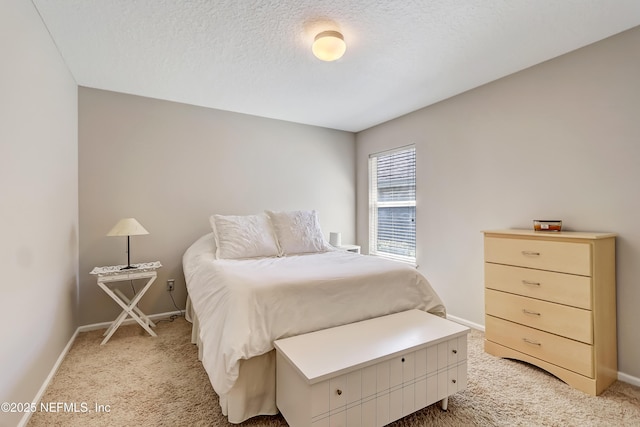 bedroom featuring light colored carpet, baseboards, and a textured ceiling