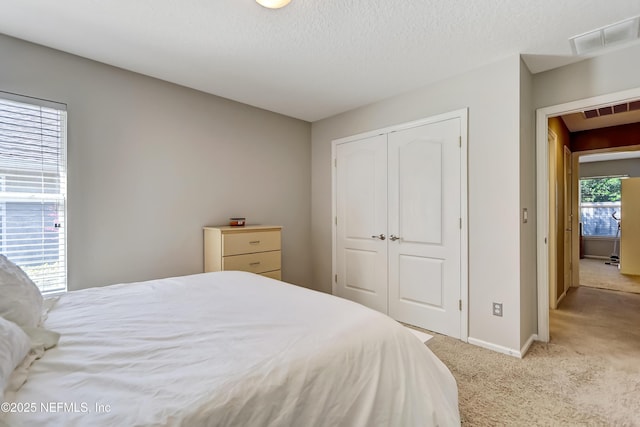 bedroom with visible vents, a textured ceiling, a closet, carpet floors, and baseboards