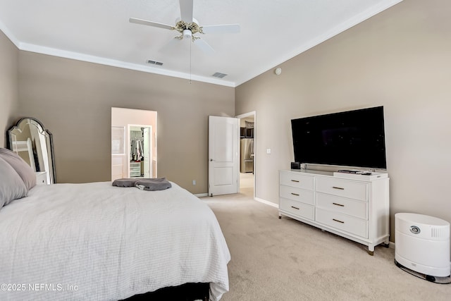 bedroom featuring visible vents, freestanding refrigerator, ornamental molding, a walk in closet, and light colored carpet