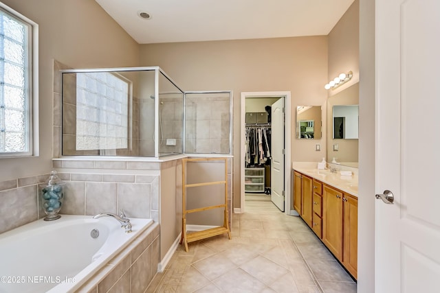 full bathroom featuring tile patterned floors, a walk in closet, tiled shower, a bath, and vanity