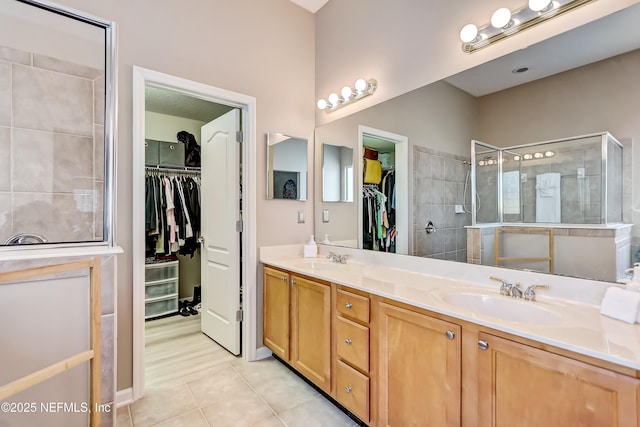 bathroom featuring a sink, tiled shower, double vanity, and tile patterned flooring