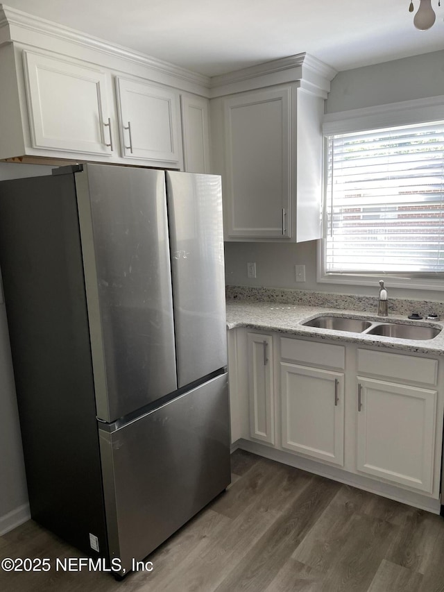 kitchen with white cabinetry, sink, and stainless steel refrigerator