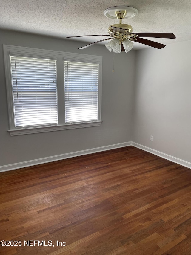 empty room featuring dark hardwood / wood-style flooring, a textured ceiling, and a wealth of natural light