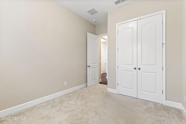 unfurnished bedroom with light colored carpet and a closet