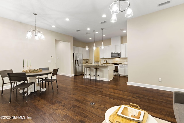 dining space featuring a notable chandelier, dark wood-type flooring, and sink