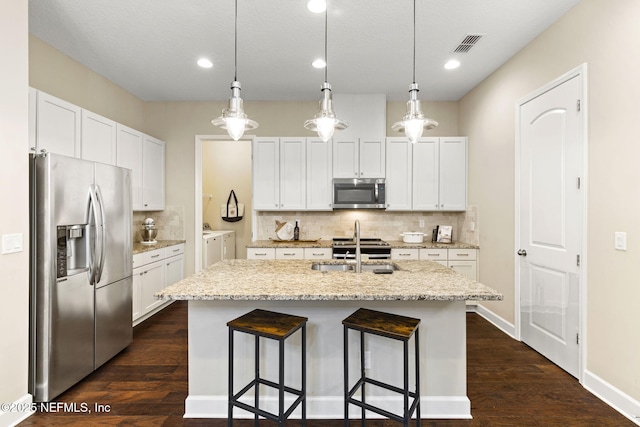 kitchen featuring a kitchen island with sink, washing machine and dryer, white cabinets, and appliances with stainless steel finishes