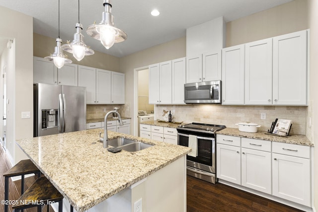 kitchen with sink, decorative light fixtures, a center island with sink, stainless steel appliances, and white cabinets