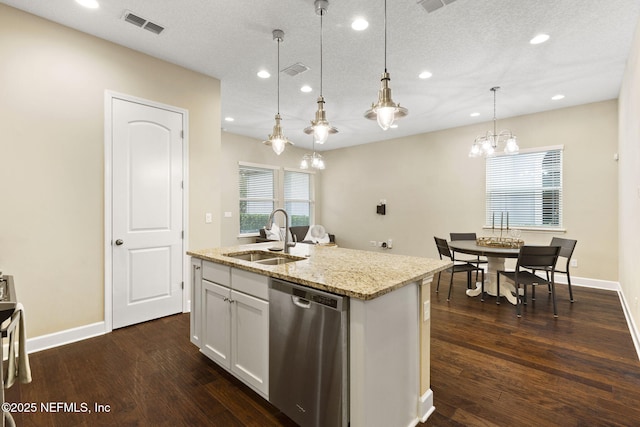 kitchen with pendant lighting, dishwasher, sink, white cabinets, and a center island with sink