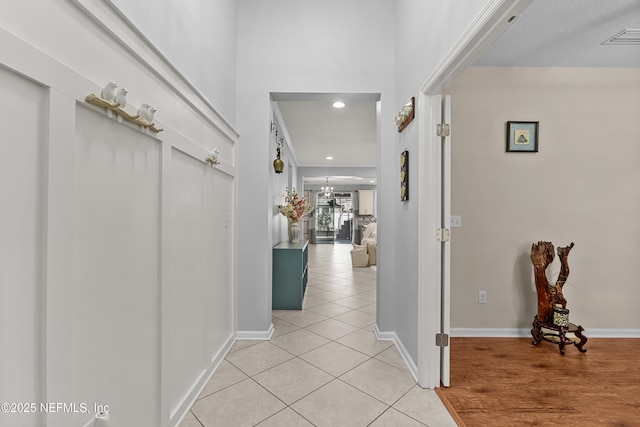 corridor featuring an inviting chandelier and light tile patterned flooring