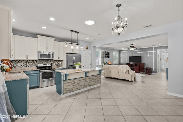 kitchen featuring sink, stainless steel appliances, white cabinets, a kitchen island, and decorative light fixtures