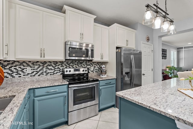 kitchen featuring hanging light fixtures, appliances with stainless steel finishes, blue cabinetry, and white cabinets