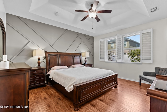 bedroom with dark hardwood / wood-style flooring and a raised ceiling