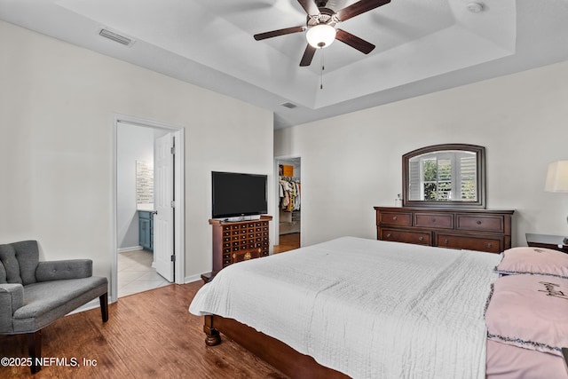 bedroom featuring a tray ceiling, light hardwood / wood-style floors, and ceiling fan