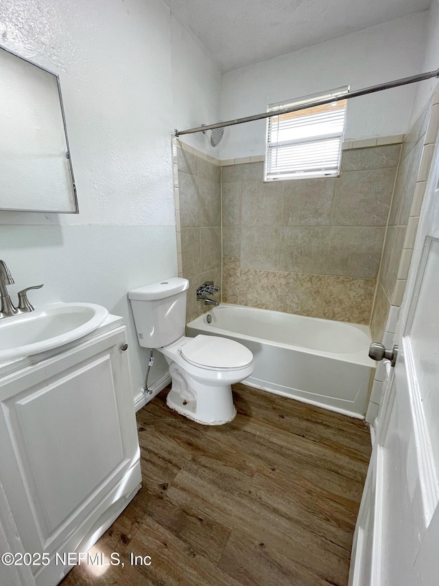 full bathroom featuring tiled shower / bath combo, wood-type flooring, vanity, and toilet