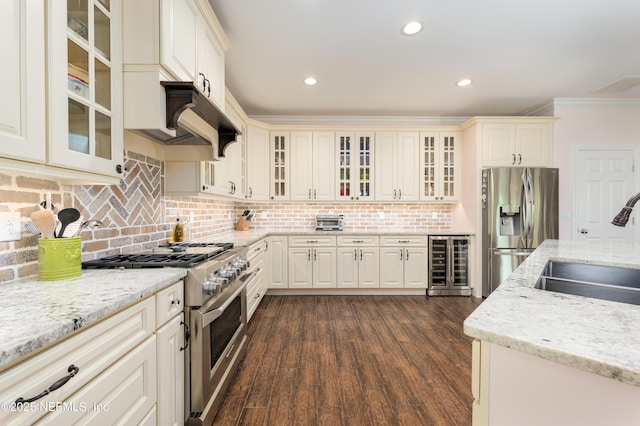 kitchen with stainless steel appliances, sink, beverage cooler, and light stone counters