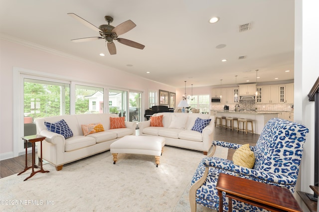 living room with sink, ornamental molding, ceiling fan, and light wood-type flooring