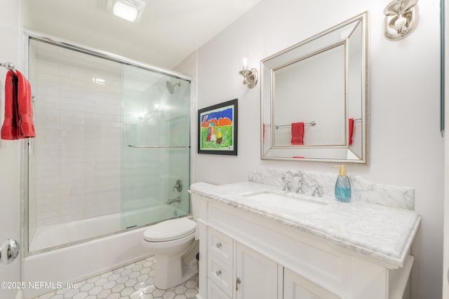 full bathroom featuring vanity, combined bath / shower with glass door, tile patterned floors, and toilet