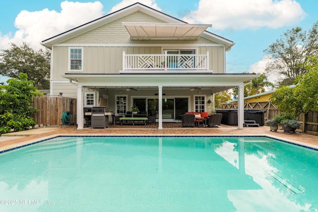 back of property featuring a pool with hot tub, ceiling fan, a patio, and a balcony