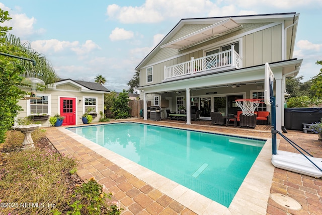 view of pool with a patio area, a hot tub, an outbuilding, ceiling fan, and a grill