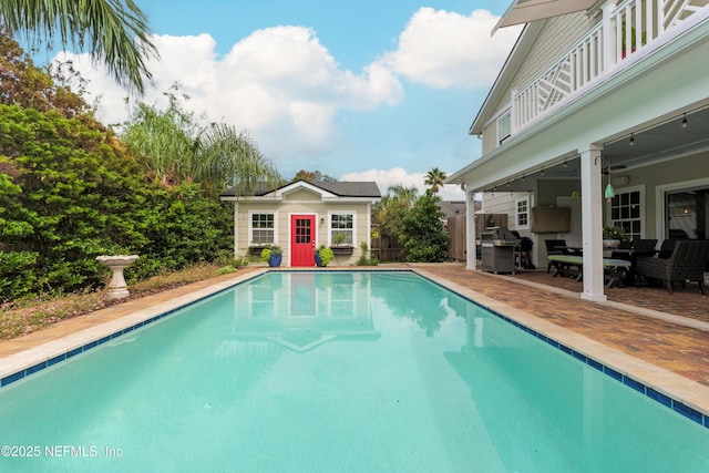 view of pool with an outbuilding, ceiling fan, area for grilling, and a patio area