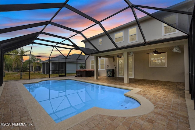 pool at dusk featuring ceiling fan, a hot tub, a patio area, and glass enclosure