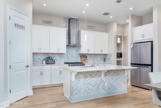 kitchen featuring white cabinetry, sink, stainless steel fridge, and wall chimney exhaust hood