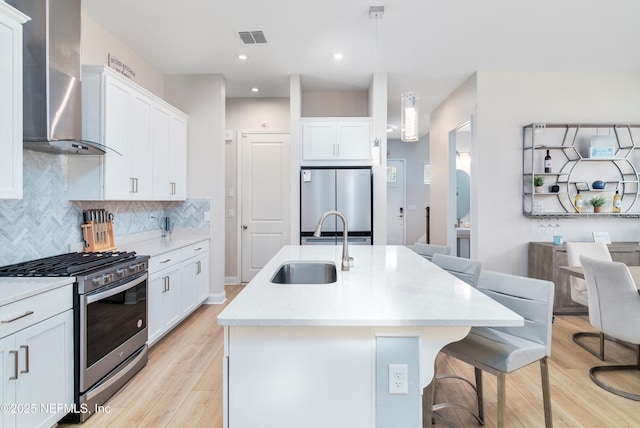 kitchen featuring stainless steel appliances, white cabinetry, pendant lighting, and wall chimney exhaust hood