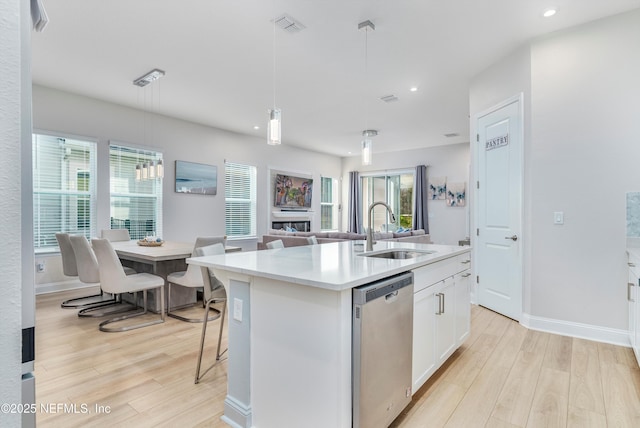 kitchen featuring dishwasher, white cabinetry, sink, hanging light fixtures, and a center island with sink