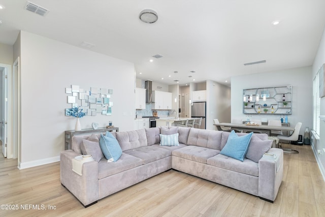 living room featuring sink and light hardwood / wood-style floors