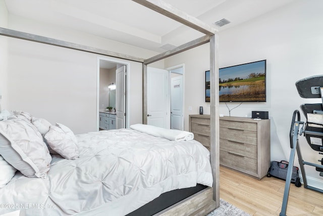 bedroom with ensuite bathroom and light wood-type flooring