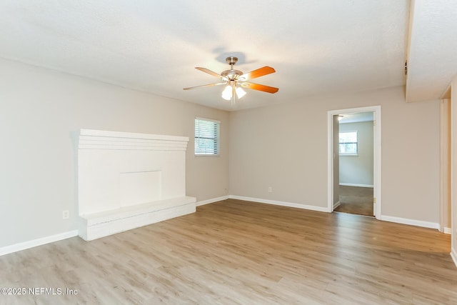 spare room featuring a textured ceiling, a wealth of natural light, light hardwood / wood-style floors, and ceiling fan