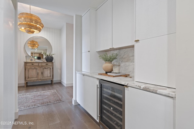 bar featuring wine cooler, backsplash, dark wood-style floors, a bar, and decorative light fixtures